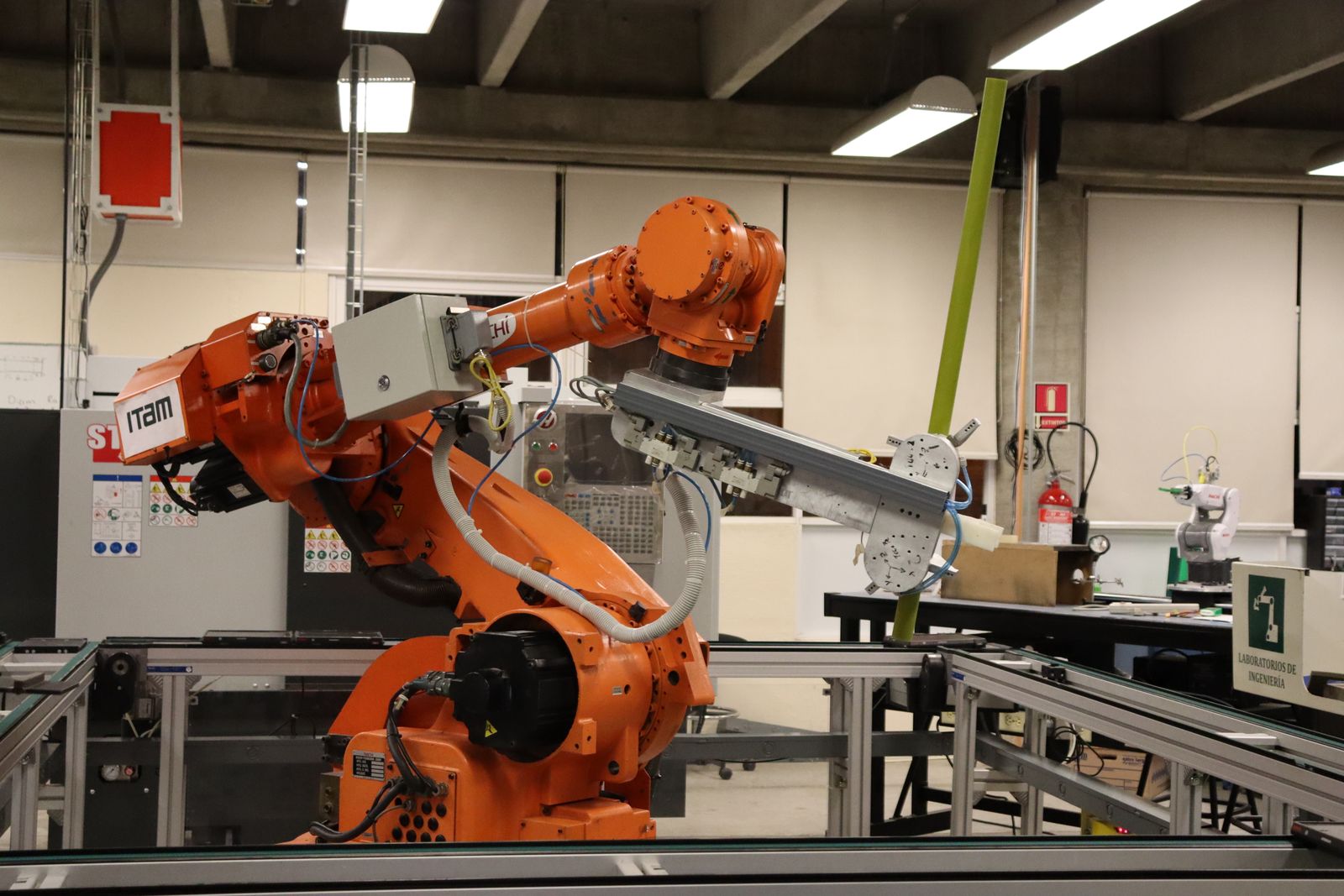 An orange industrial robotic arm on a conveyor line in a university engineering lab