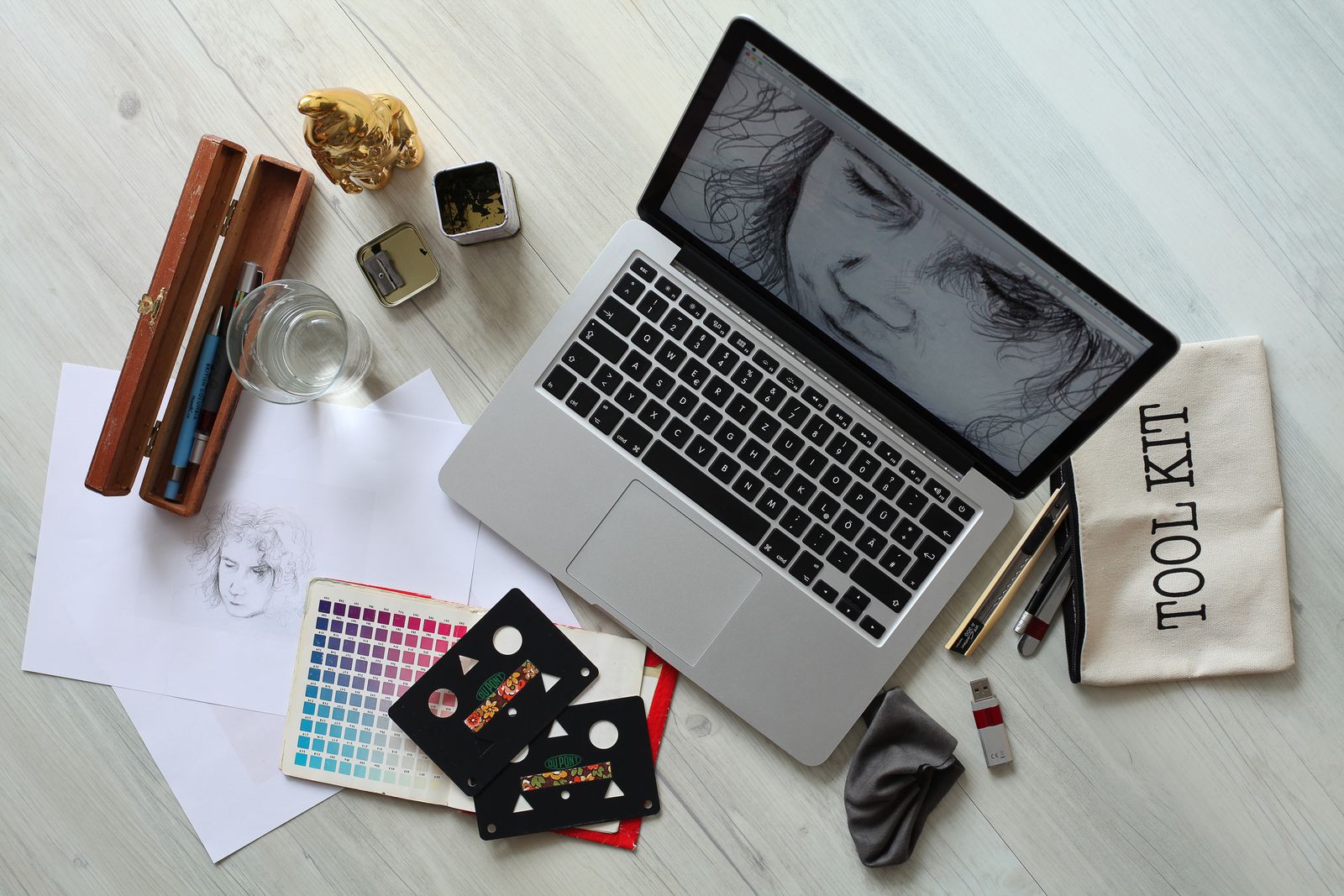 Top view of a design workspace with a laptop, sketch supplies, and a color palette