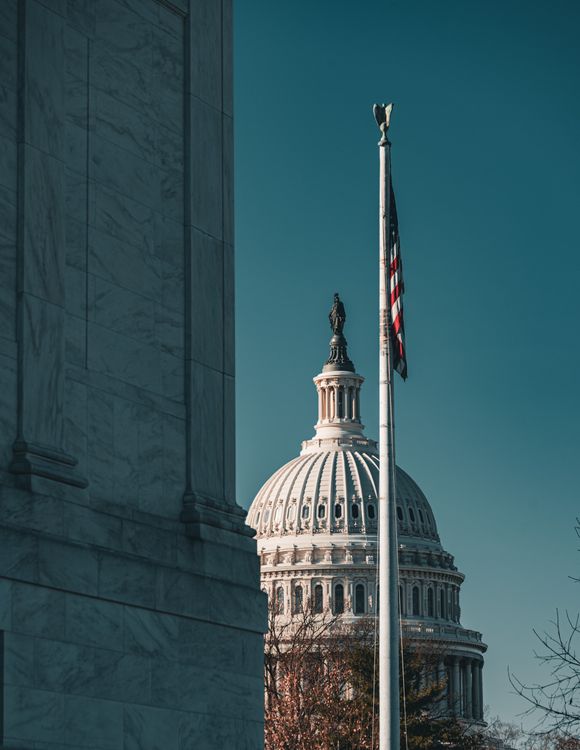 US Capitol dome with an American flag on a clear day