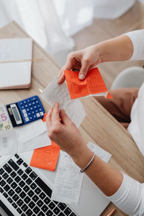 Top view of a person organizing finances with a calculator, receipts, and notes at a desk; illustrative stock photo, not DualEntry staff or systems