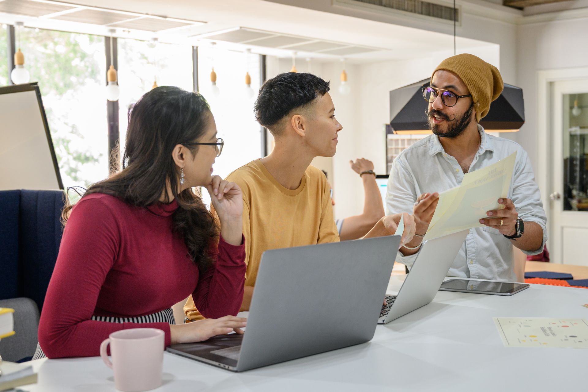 Coworkers collaborating at laptops in a modern office