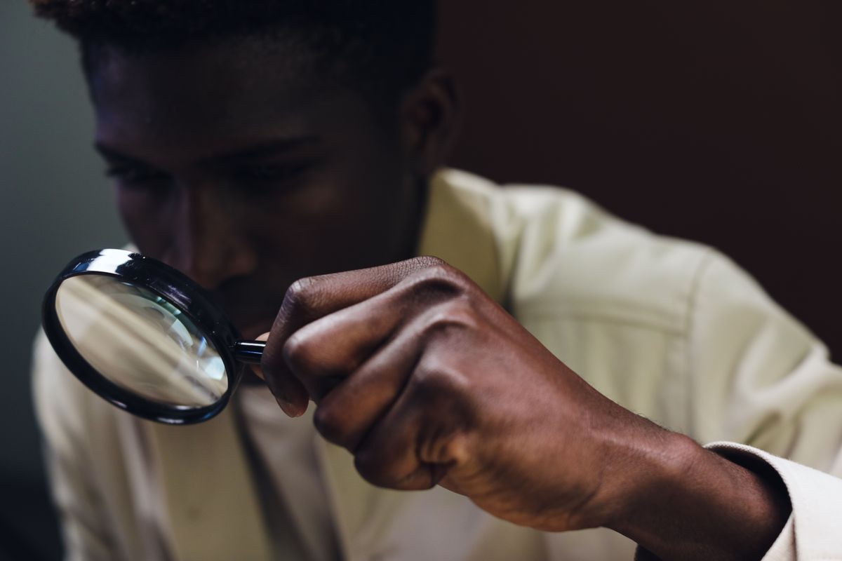 A person examining something closely through a magnifying glass