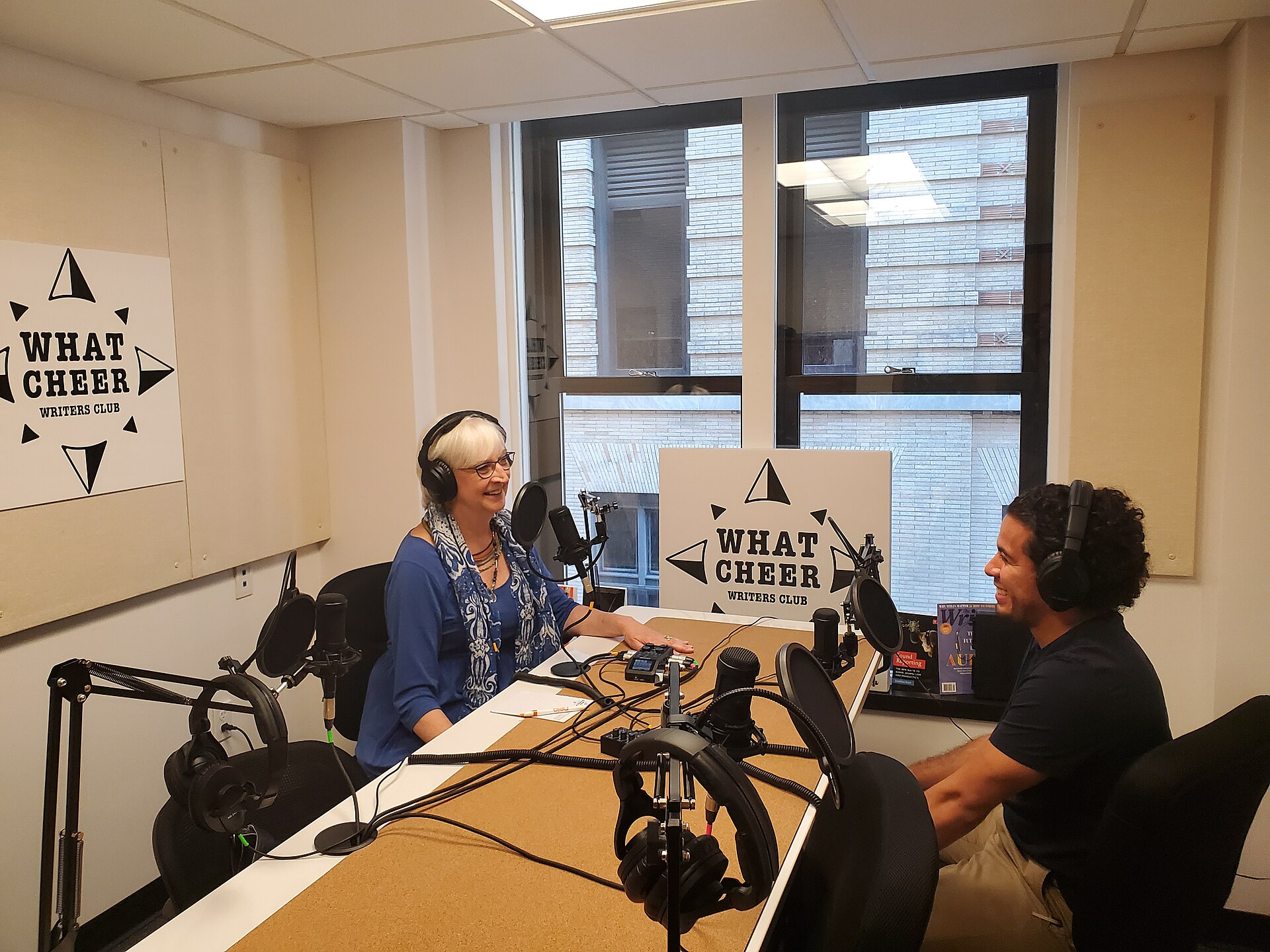 Two people recording a podcast with microphones and headphones