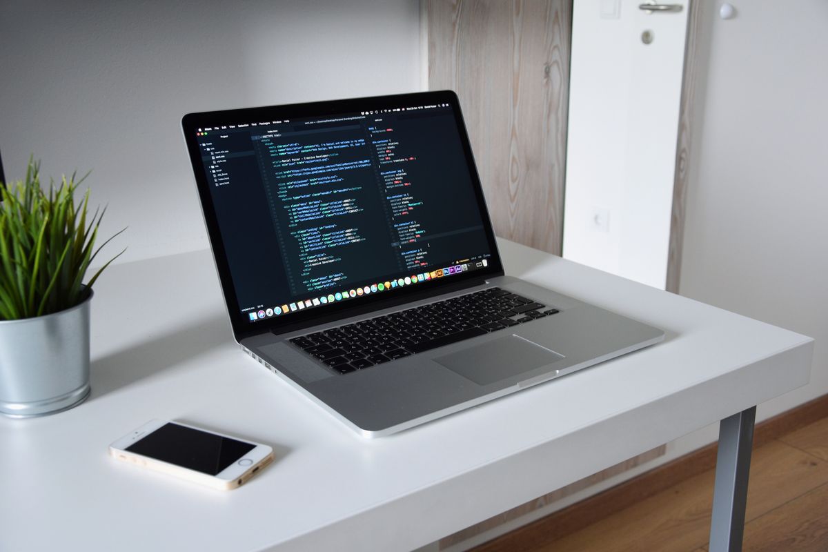A laptop on a white desk with a code editor open on its screen