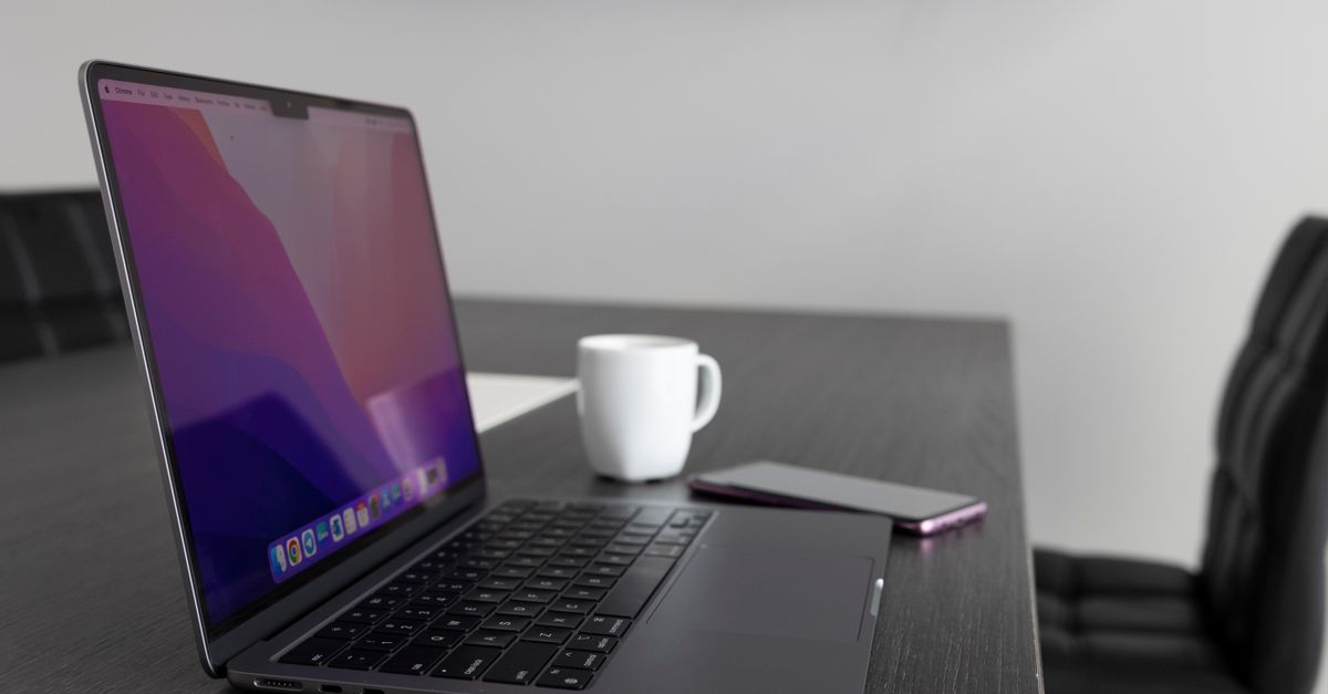 Laptop on a workspace desk with a coffee cup and smartphone