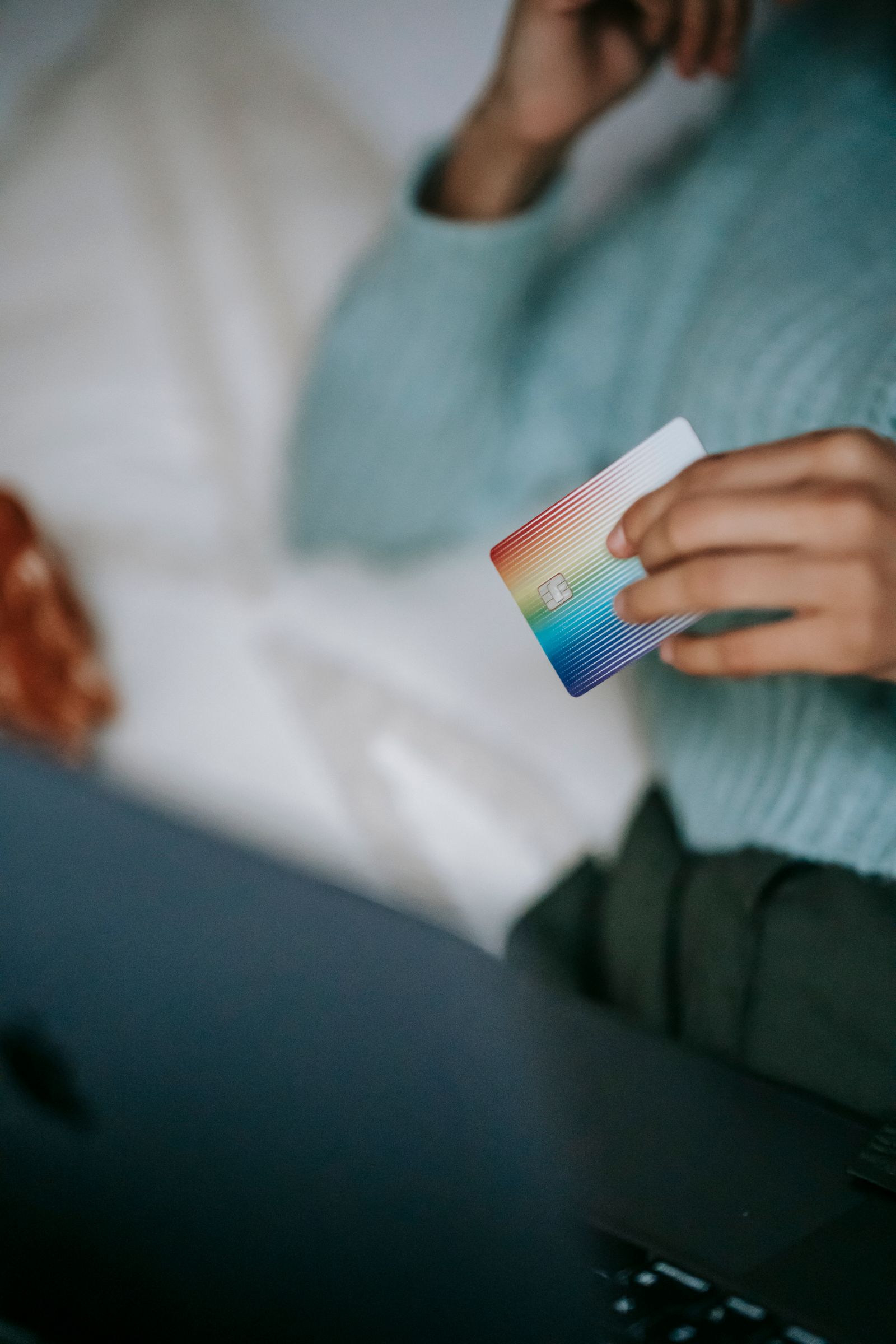 A shopper holding a credit card over a laptop while buying online